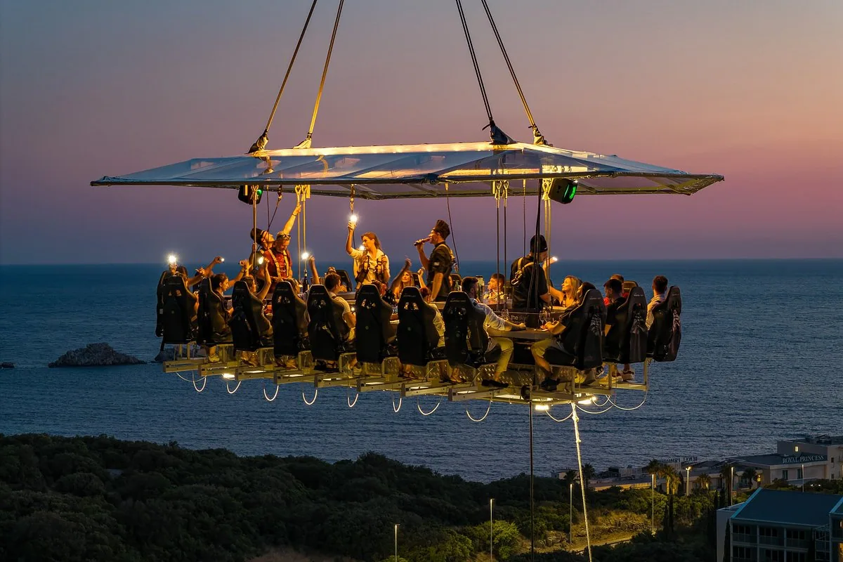Guests suspended high above the ground enjoying dinner with scenic city views